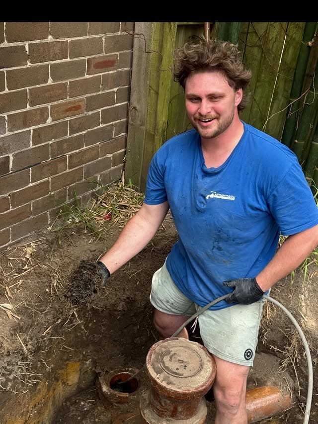 AFP plumber clearing tree-root blockage from sewer drain